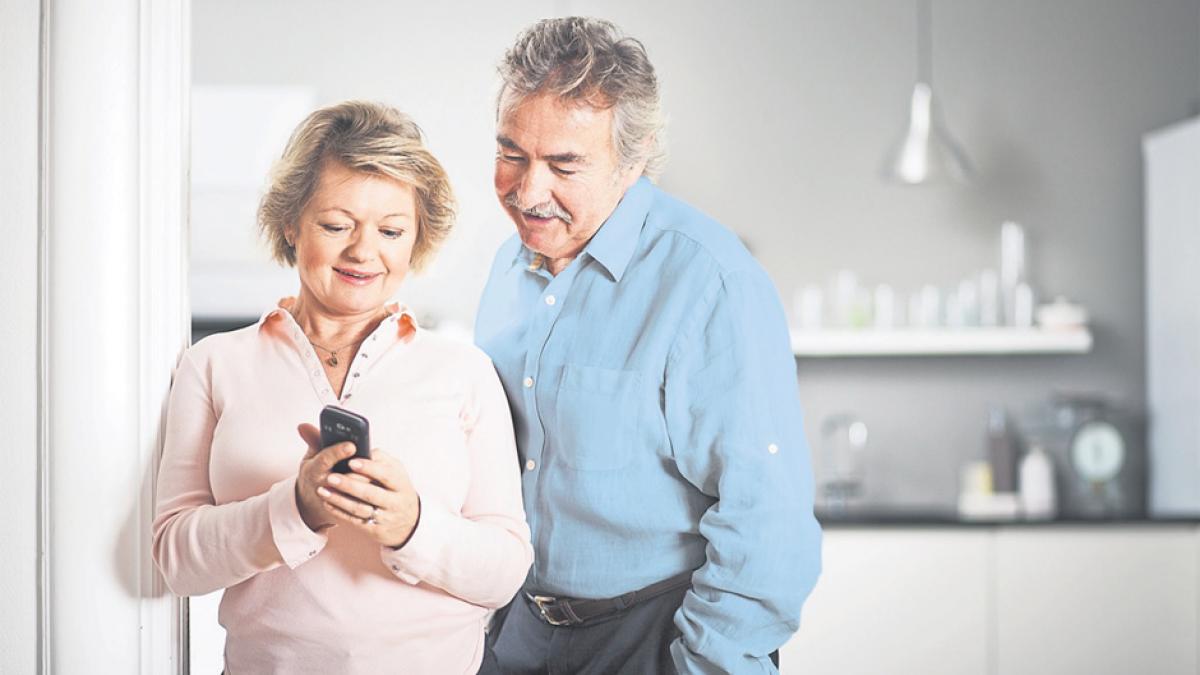 Elderly couple happily using mobile phone