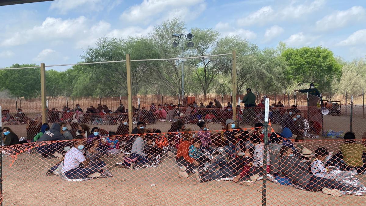 Group of migrant children waiting under a bridge to be processed.