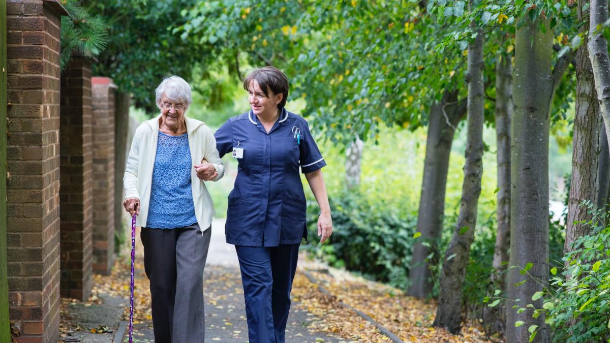 elderly woman walking with caregiver