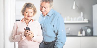 Elderly couple happily using mobile phone