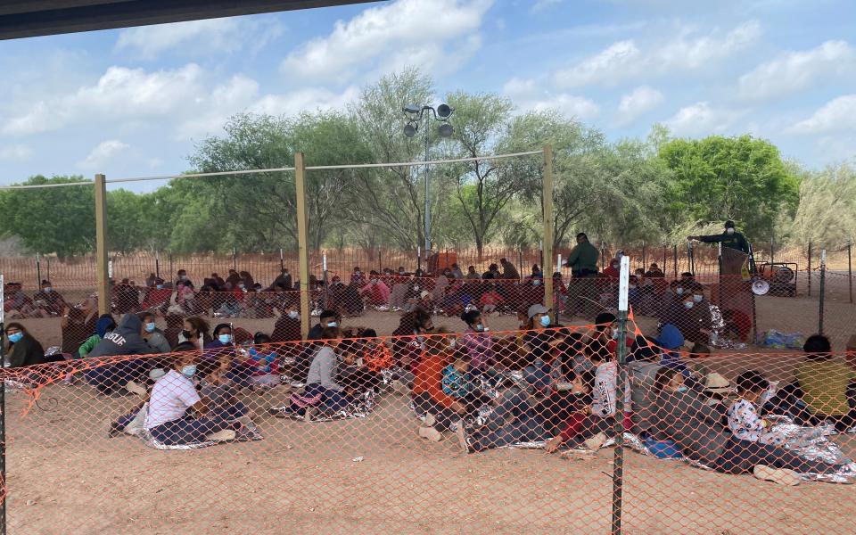 Group of migrant children waiting under a bridge to be processed.