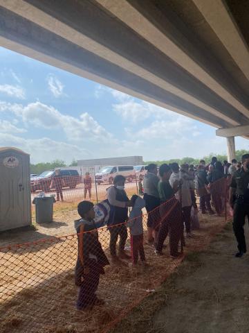 Temporary outdoor processing site under bridge.