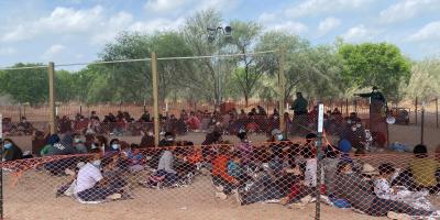 Group of migrant children waiting under a bridge to be processed.